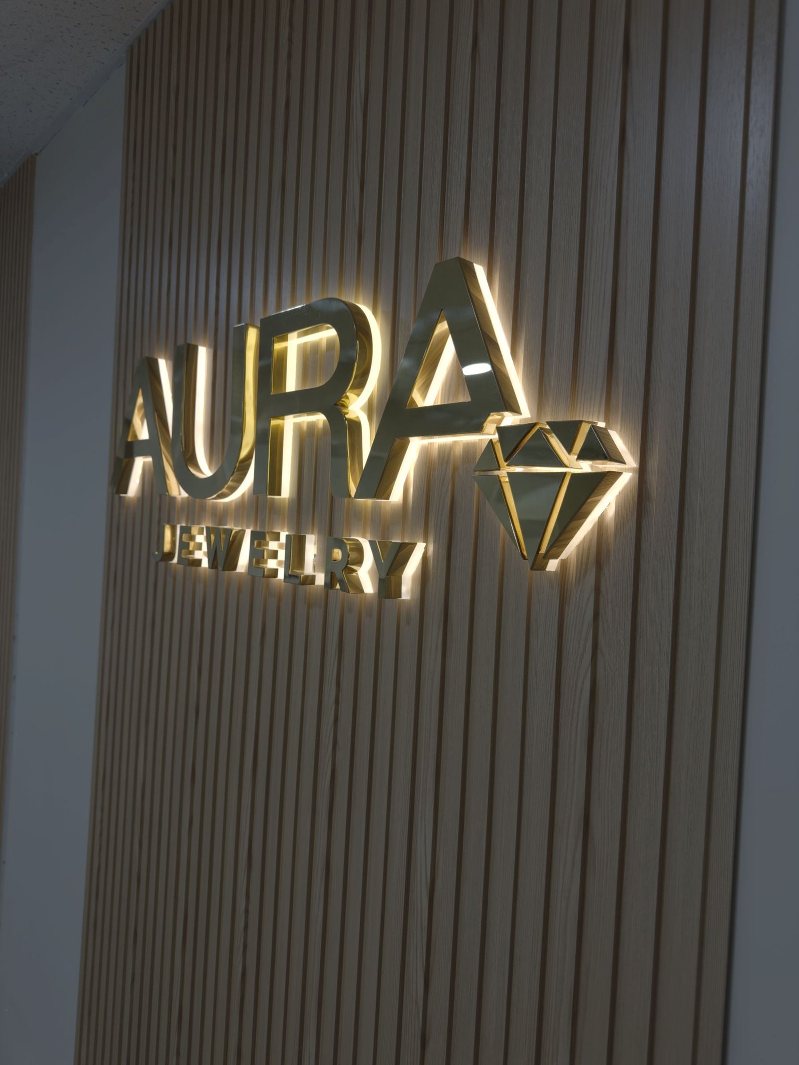 Halo-lit gold letters for Aura Jewelry on a slat wall